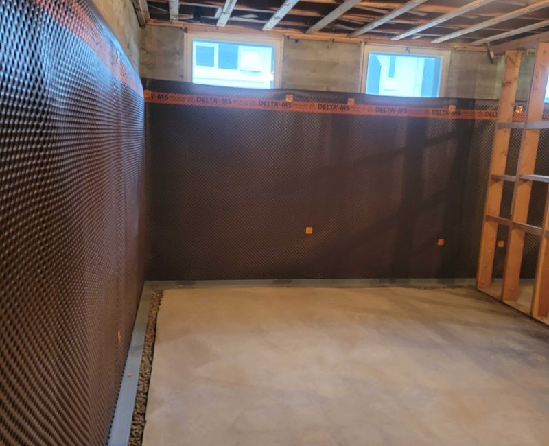 Interior view of a construction space featuring exposed wooden framing, a concrete wall, and a textured floor ready for finishing